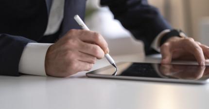 Businessman signing digital contract on tablet using stylus pen