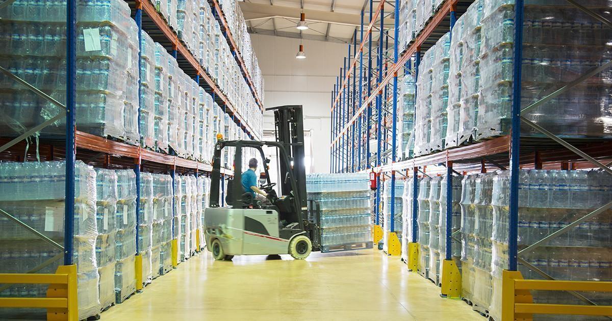 Worker moving pallets with forklift in warehouse